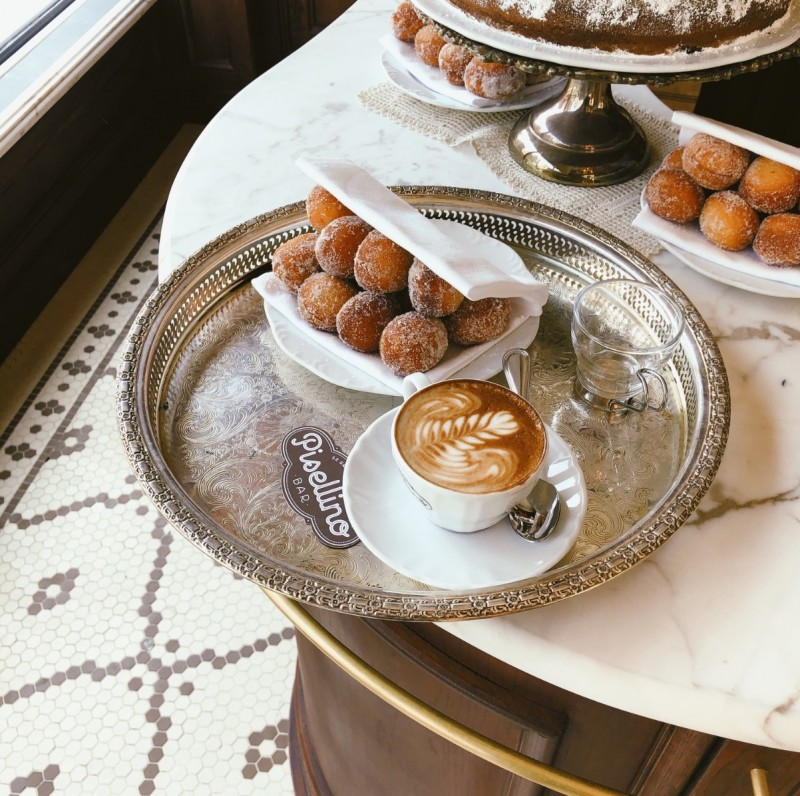 cappuccino and bomboloni on a silver tray at bar pisellino