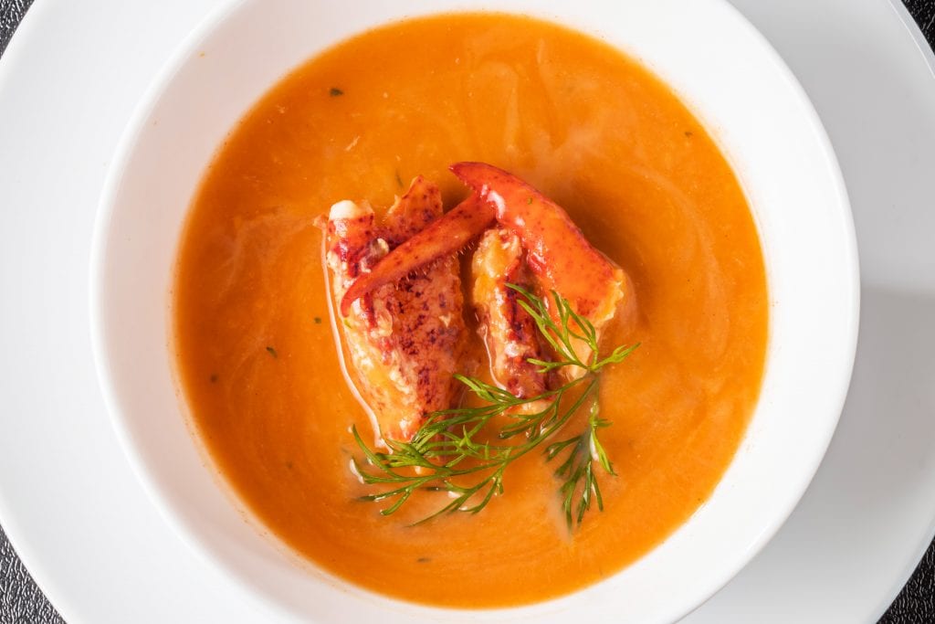 Lobster Bisque in a white bowl with greens.