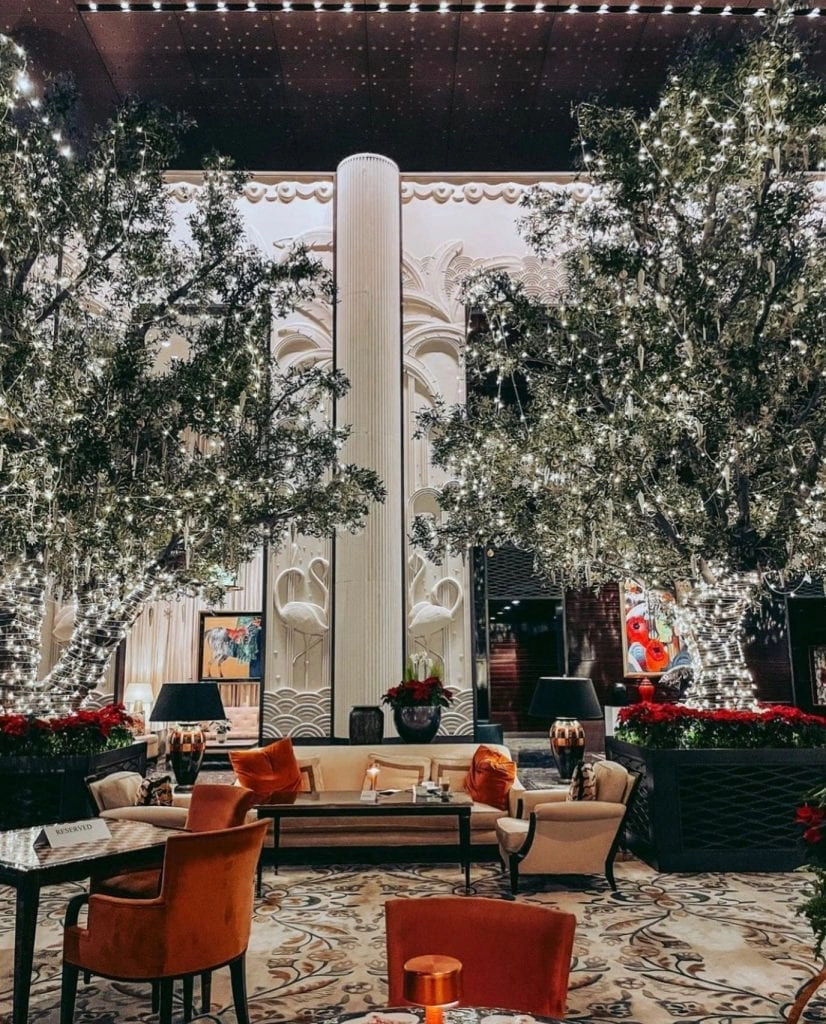 hotel interior with grey walls, brown ceiling, full sized trees, orange chairs