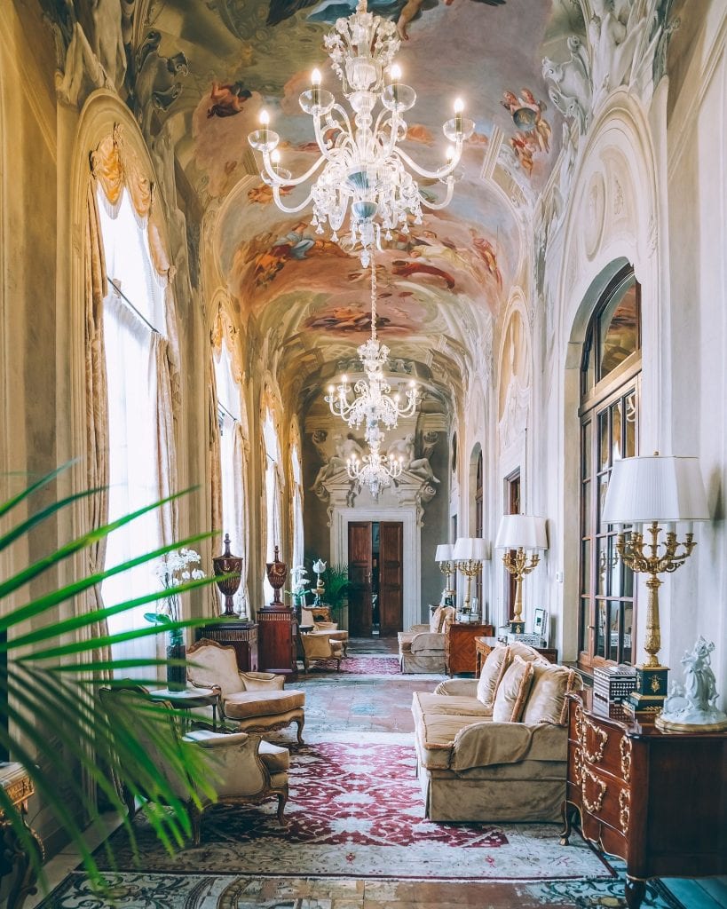 hotel interior with painted ceilings, dangling chandeliers, palm plants and sofas, best four Seasons in the world