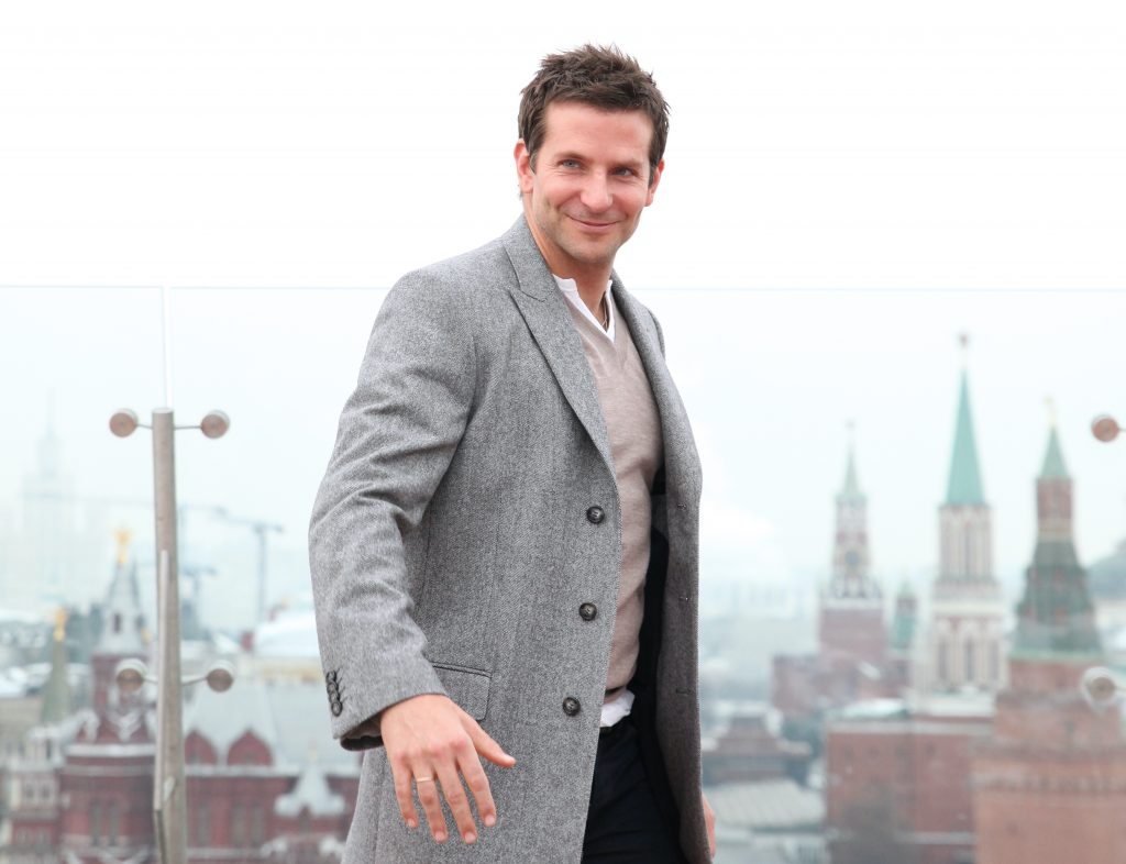 a man in a grey coat against a backdrop of a city skyline and grey sky