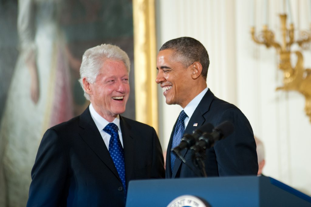 Bill Clinton standing next to Obama at a podium. 