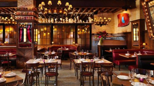 wooden chairs and tables in a brightly lit brown and red toned restaurant, Dirty French NYC