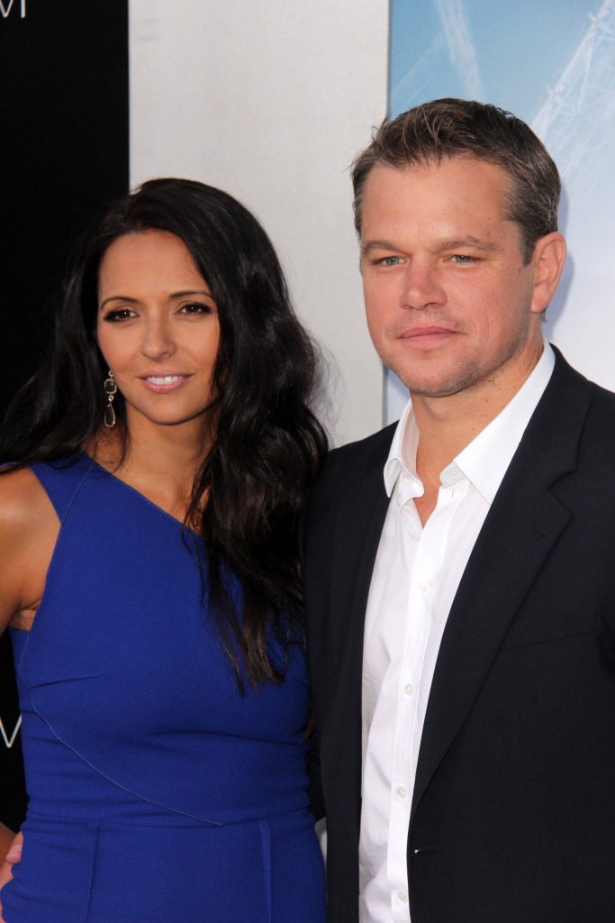 woman with long black hair in a blue dress with a man in a dark suit and white shirt,matt damon vacation