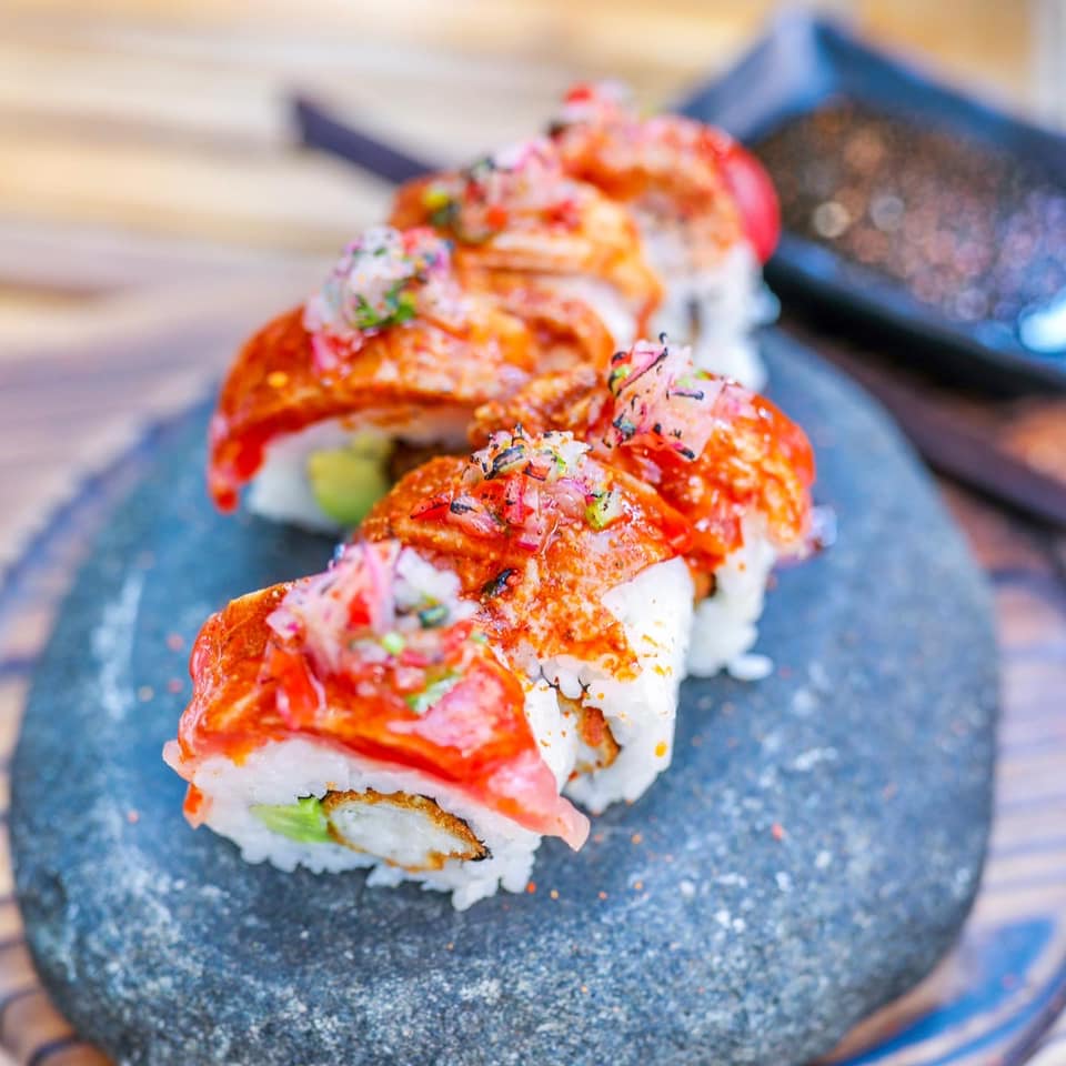 red topped white sushi rolls on a grey stone plate
