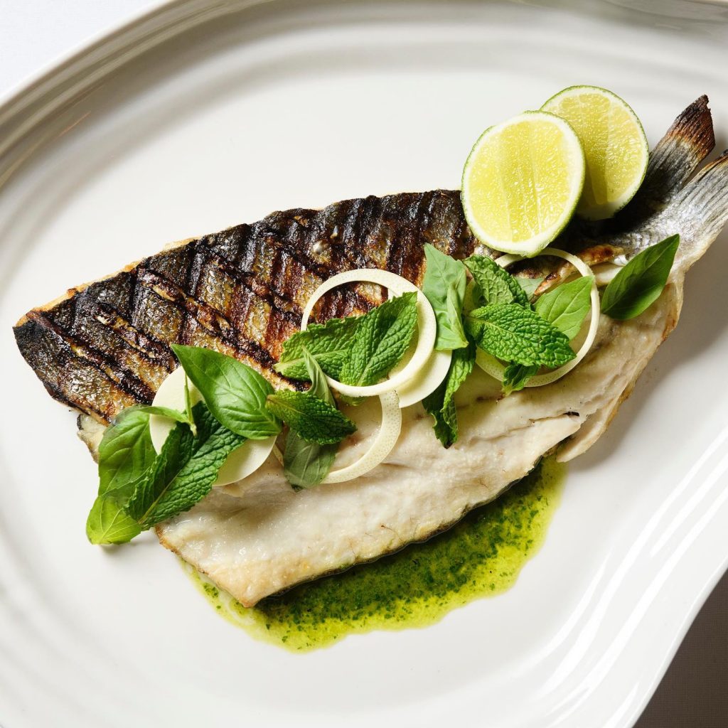 Large fish served with mint leaves and mint sauce at Saint Theo's NYC.