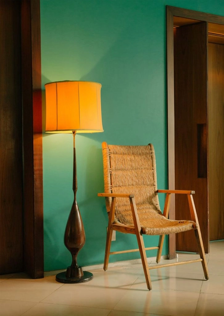 a brown wicker chair and tall wooden lamp on a marble floor against a vivid green wall