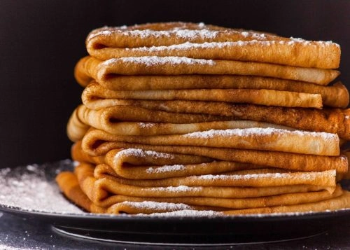 Stack of Crepes with powered sugar on dark background