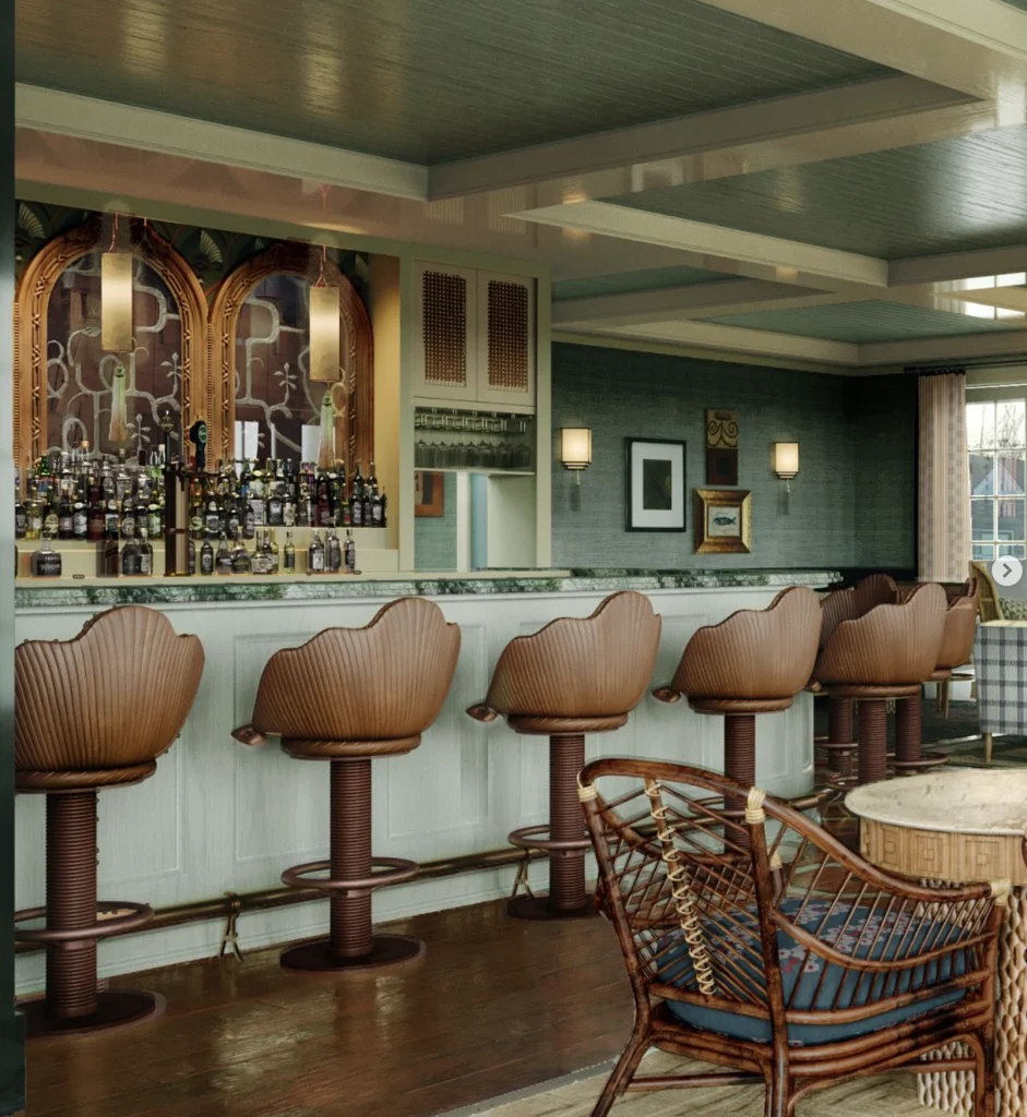 An elegant coastal-inspired hotel bar with shell-backed leather stools, woven lounge seating, green marble countertops, and muted nautical interiors in a luxury Hamptons boutique hotel.