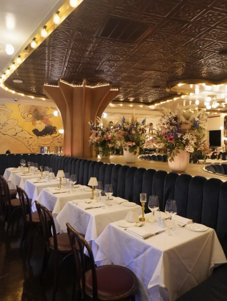 Elegant cabaret-inspired dining room at Maison Close featuring dramatic lighting, plush seating, and theatrical Parisian supper club décor in the Hamptons.